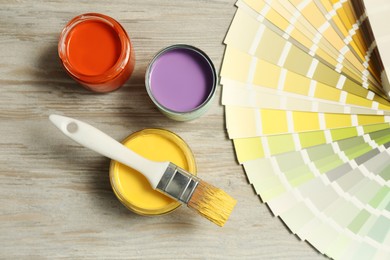 Photo of Different paints with brush and palette on light wooden background, flat lay