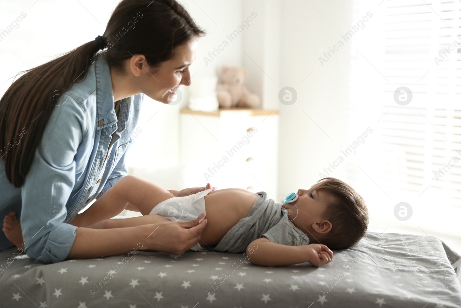 Photo of Mother changing baby's diaper on table at home