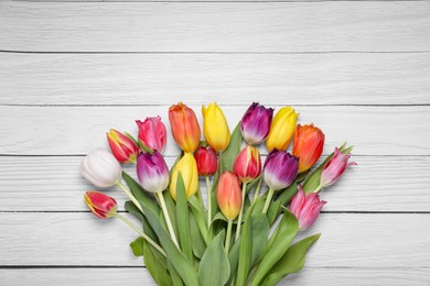 Photo of Beautiful colorful tulip flowers on white wooden table, top view