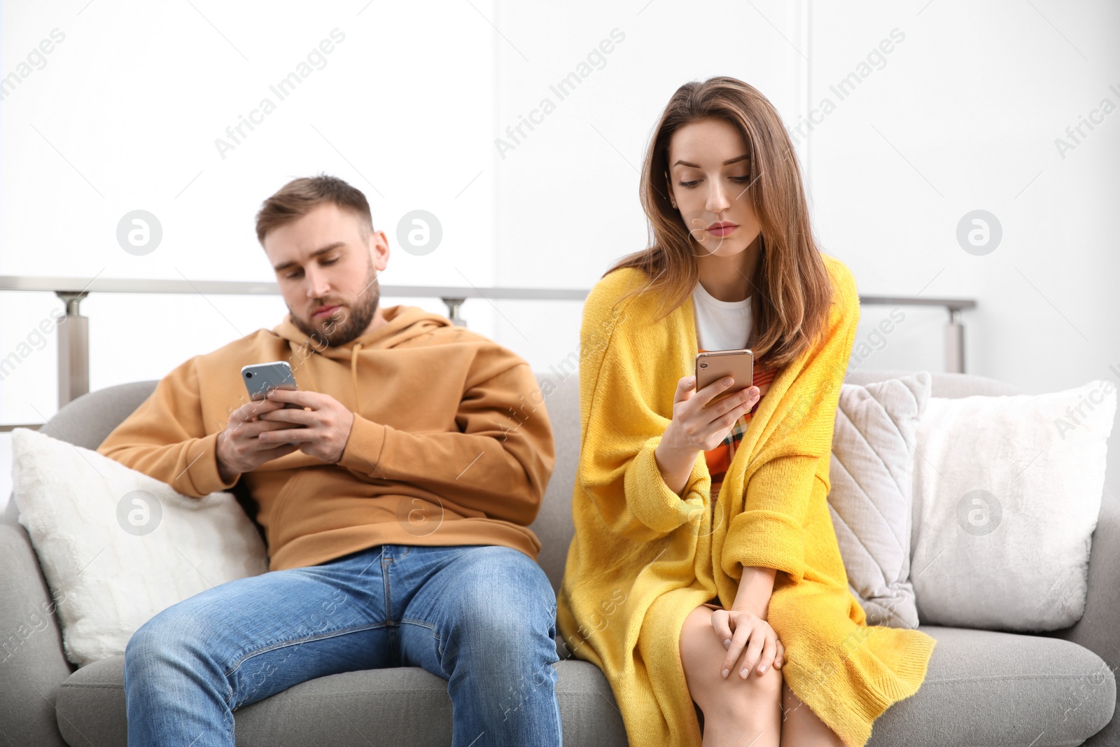 Photo of Couple addicted to smartphones ignoring each other at home. Relationship problems