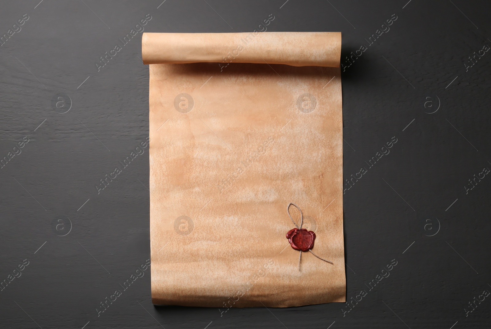 Photo of Sheet of old parchment paper with wax stamp on grey wooden table, top view. Space for text