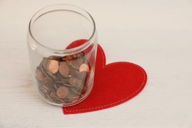 Photo of Red heart and donation jar with coins on light background
