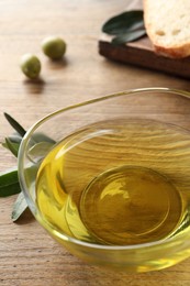 Glass bowl of olive oil on wooden table, closeup