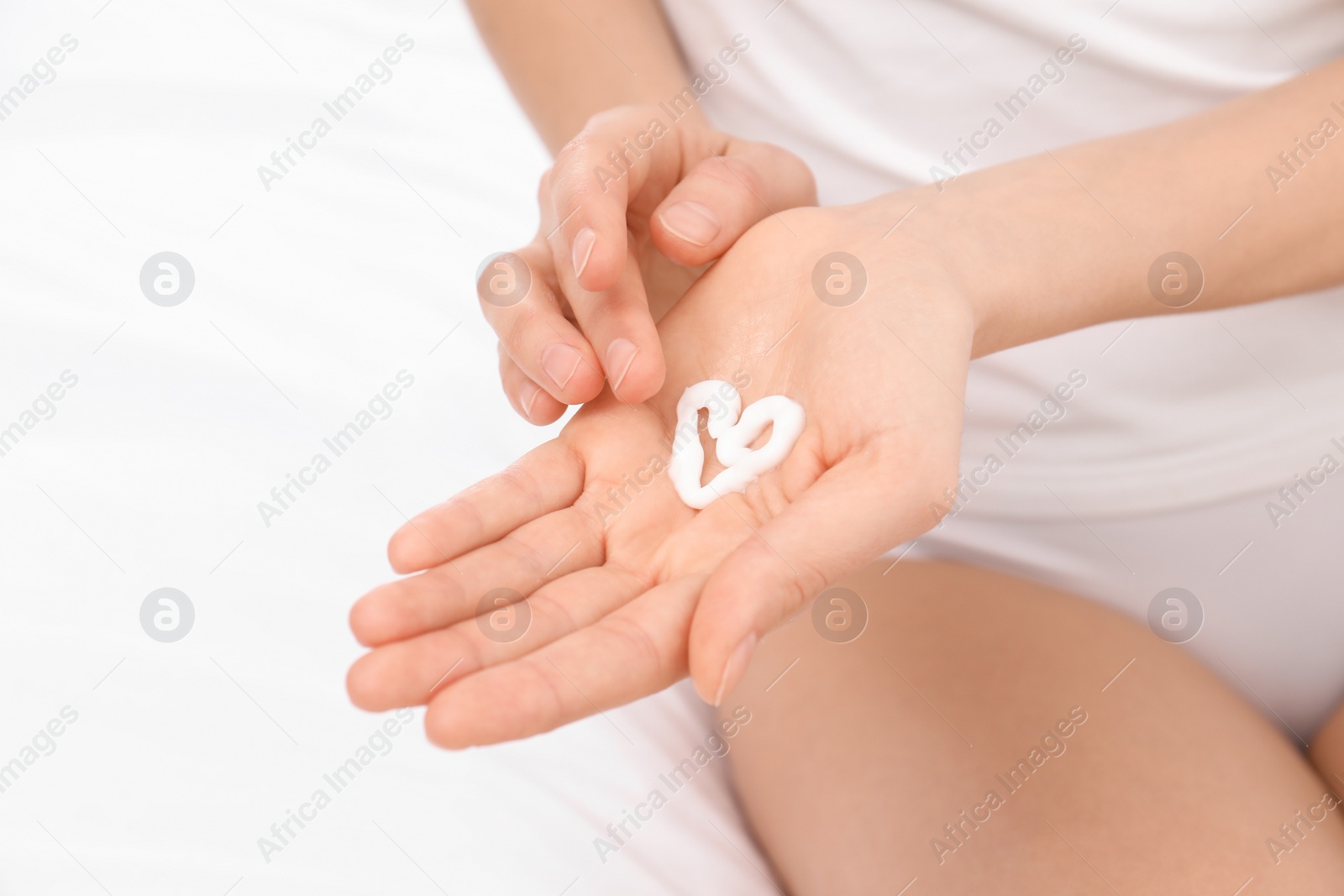 Photo of Young woman with heart made of cream on her hand, closeup. Beauty and body care