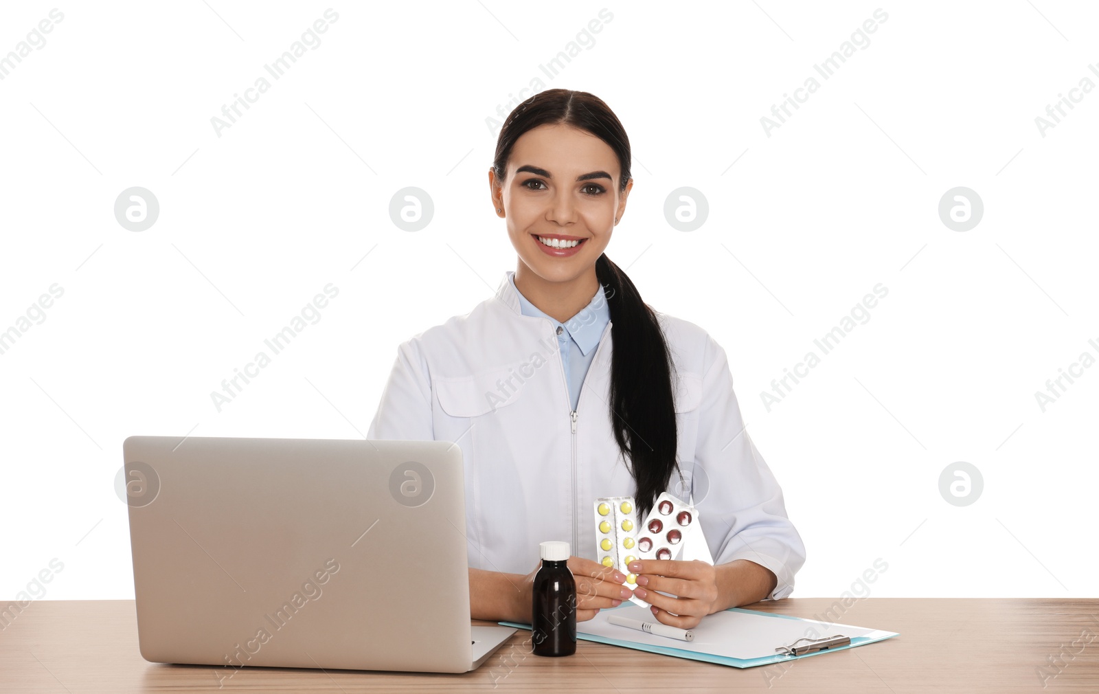 Photo of Professional pharmacist with pills and laptop at table against white background