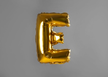 Golden letter E balloon on grey background