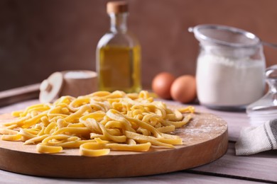 Board with homemade pasta on wooden table