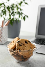 Photo of Chocolate chip cookies on light gray table at workplace