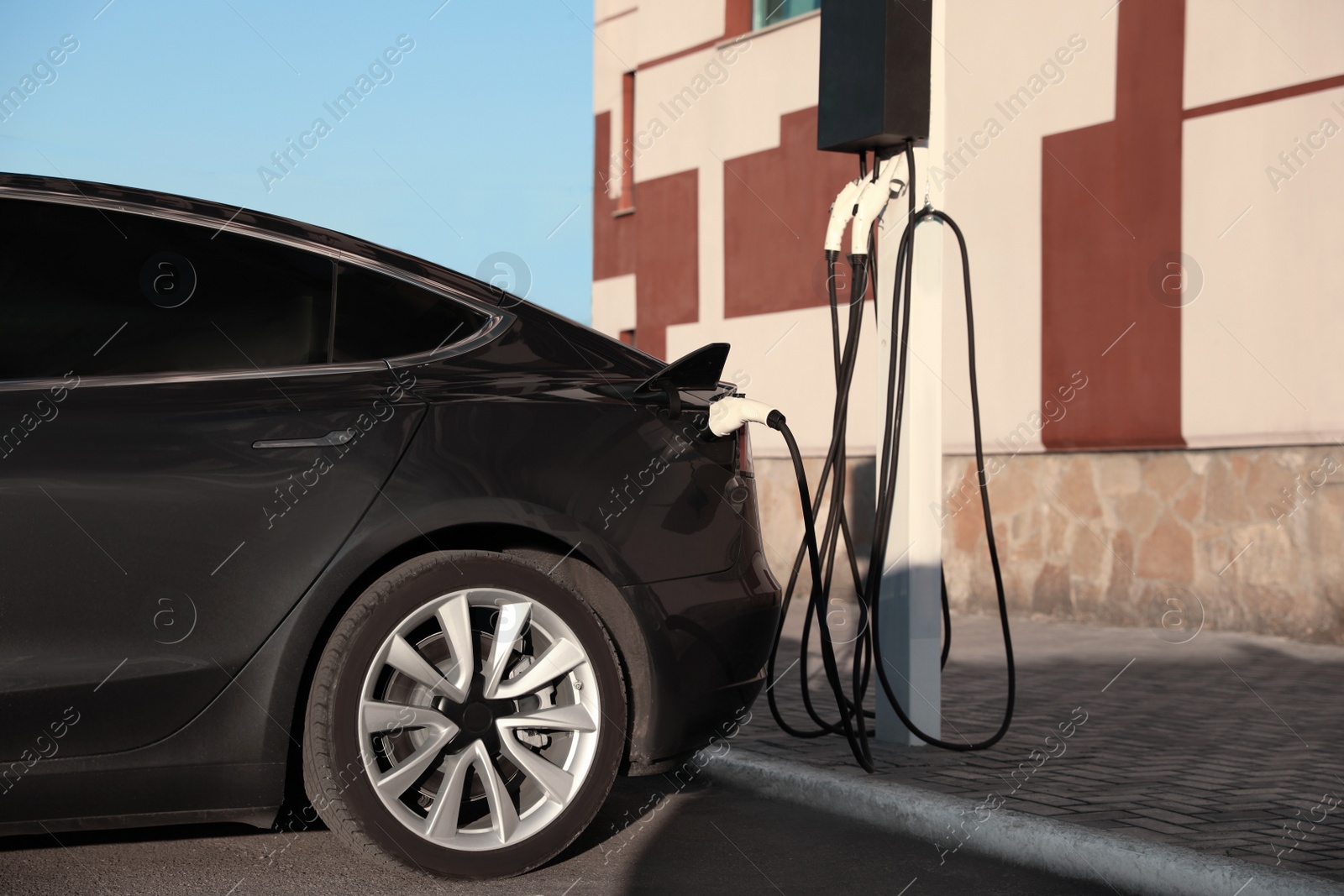 Photo of Charging modern electric car from station outdoors