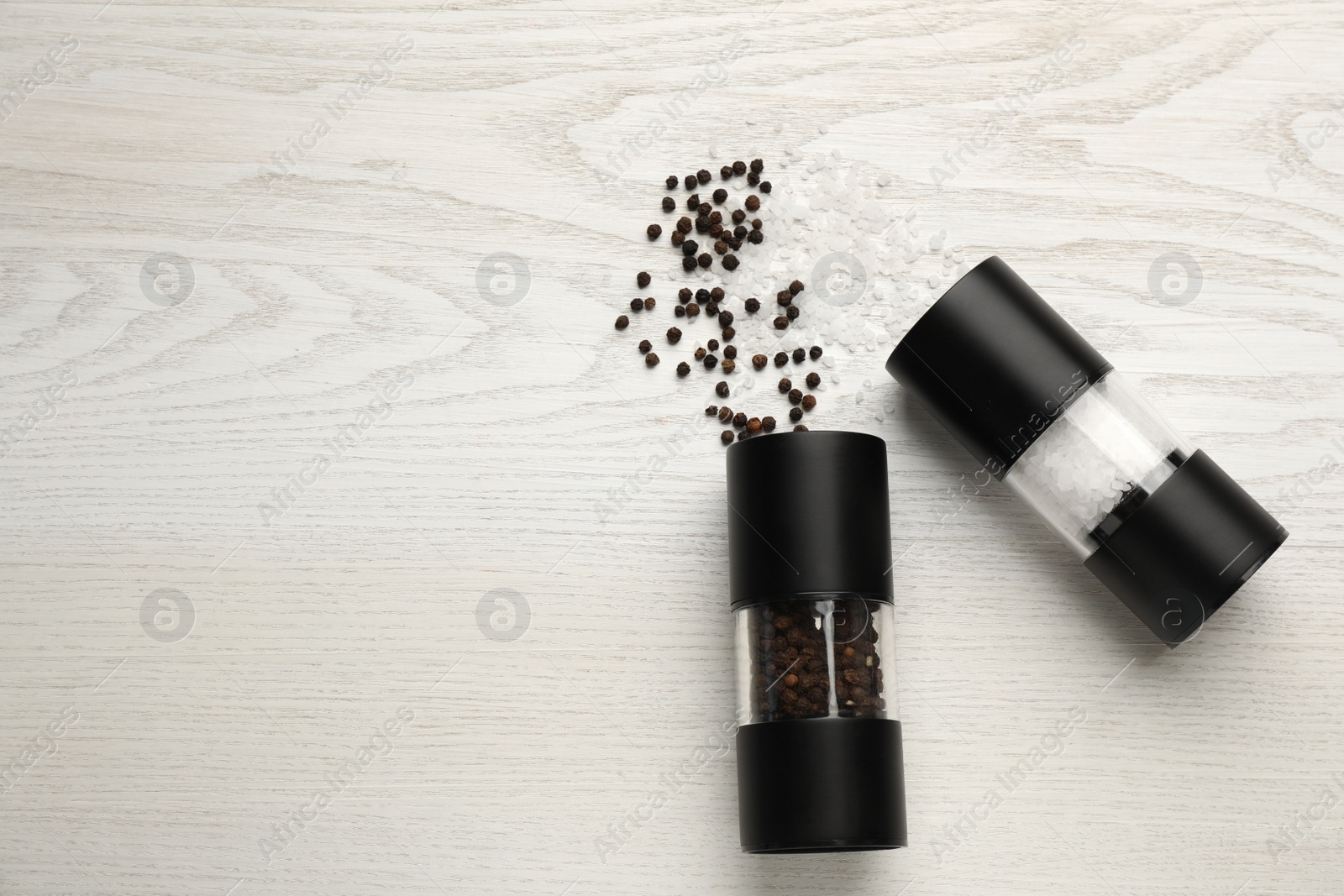 Photo of Salt and pepper shakers on white wooden table, flat lay. Space for text