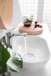 Photo of Sink with running water in stylish bathroom interior
