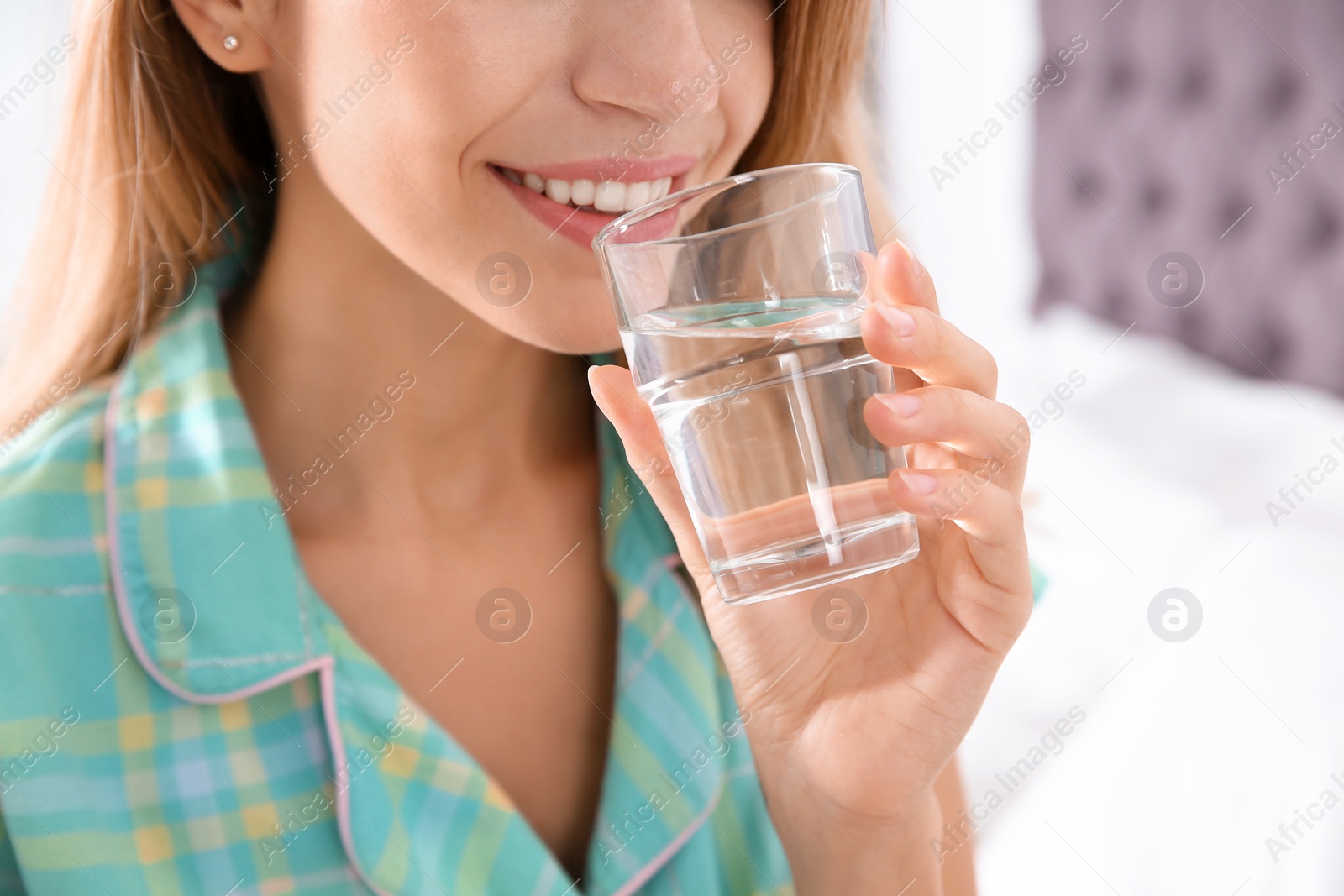 Photo of Young woman drinking water from glass indoors, closeup