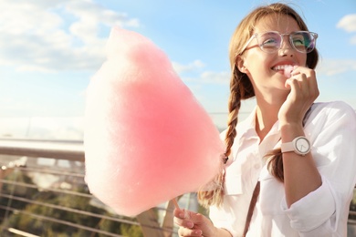 Young woman with cotton candy outdoors on sunny day