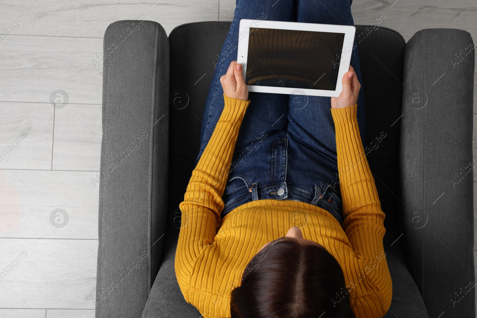 Photo of Woman working with tablet in armchair, top view