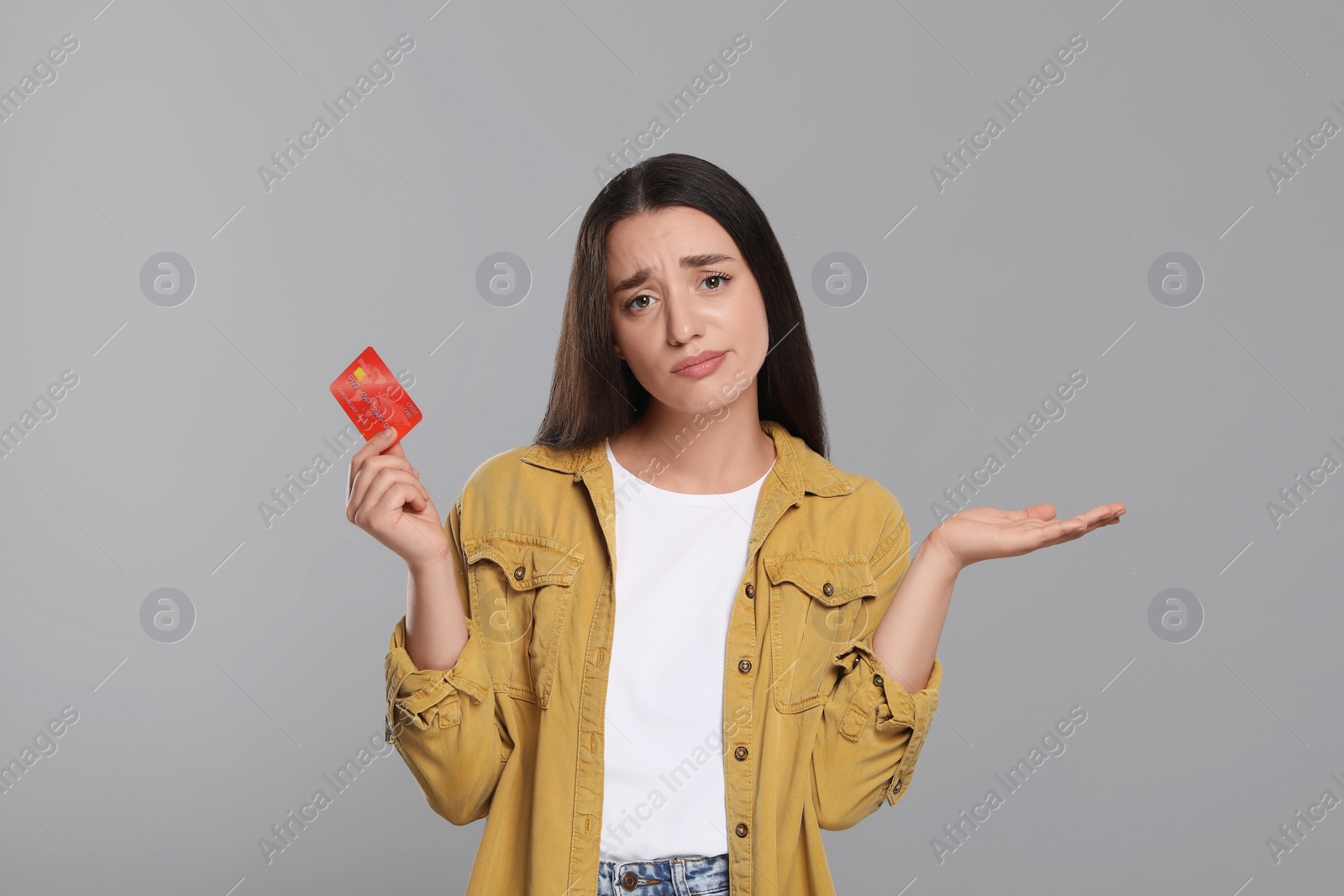 Photo of Confused woman with credit card on light gray background. Debt limit