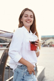 Photo of Young woman with refreshing drink on city street