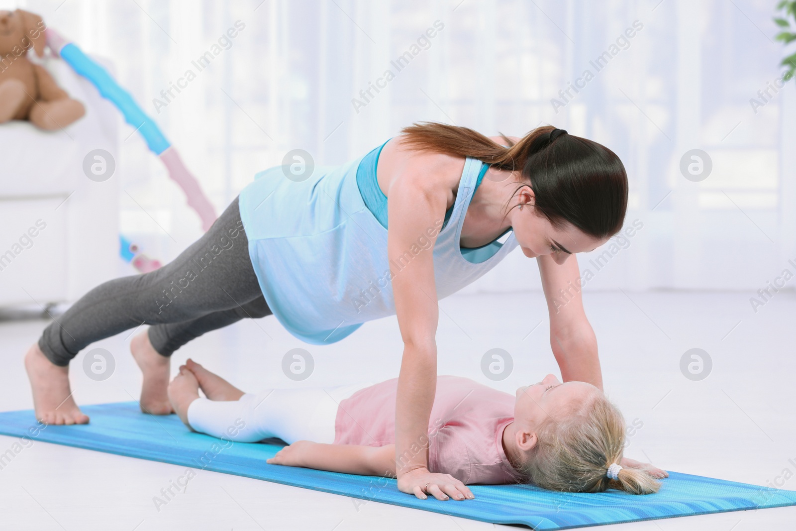 Photo of Sportive woman doing fitness exercises with daughter at home