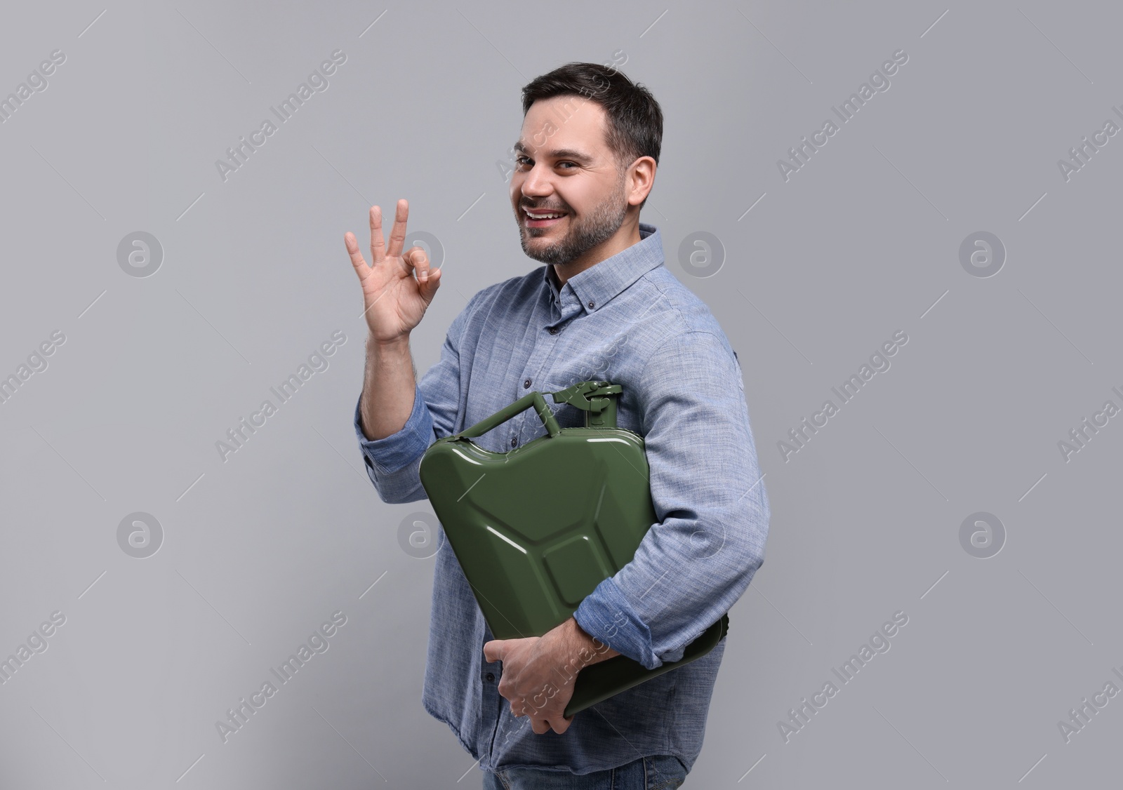 Photo of Man holding khaki metal canister and showing OK gesture on light grey background