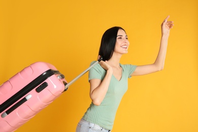 Photo of Beautiful woman with suitcase for summer trip on yellow background. Vacation travel