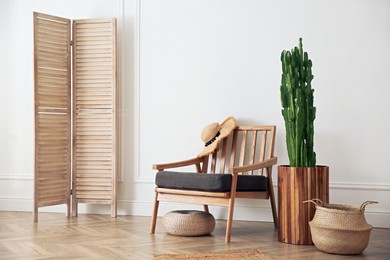 Stylish room interior with beautiful potted cactus and armchair