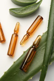 Skincare ampoules and aloe leaves on white background, closeup