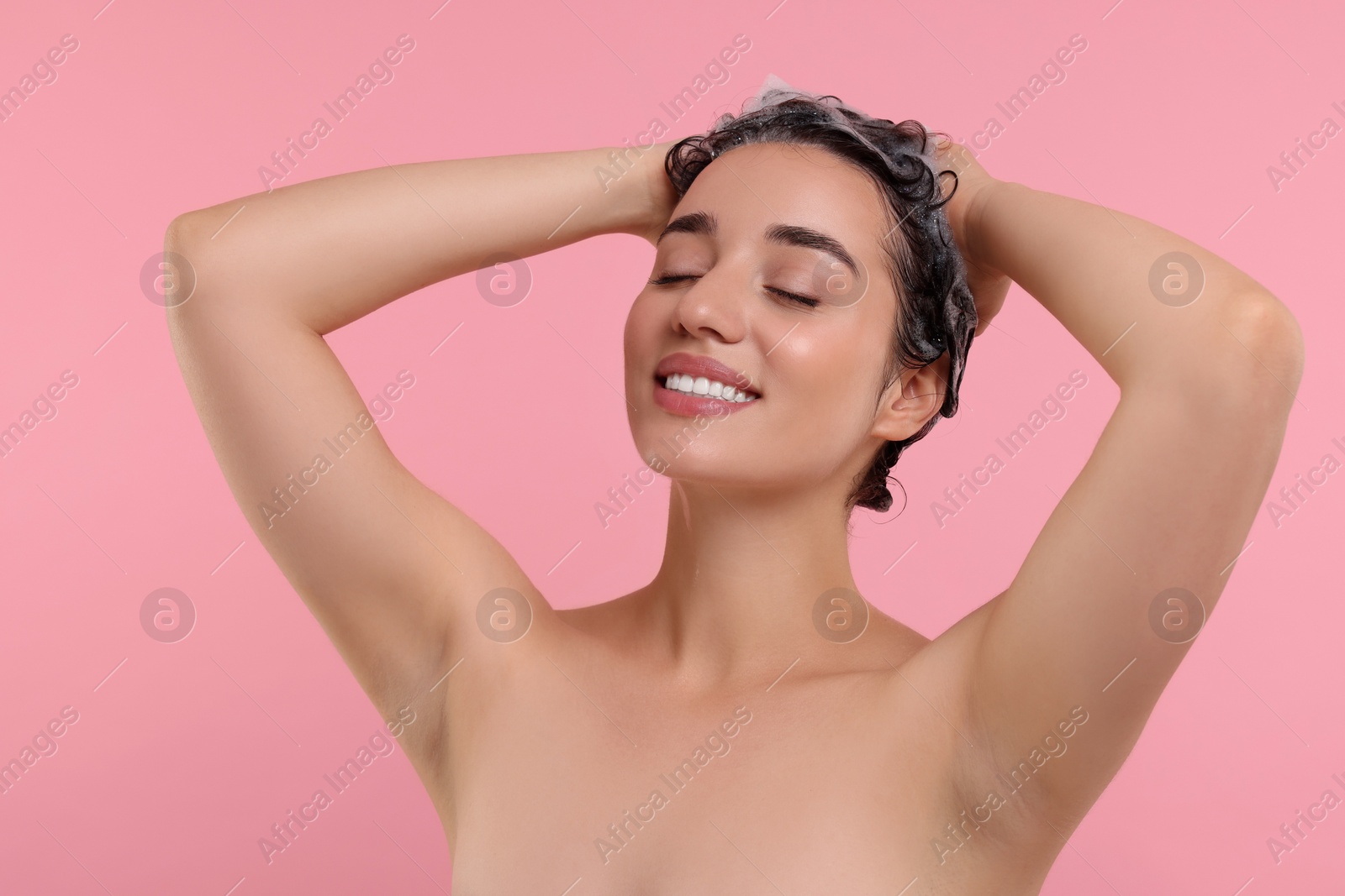 Photo of Portrait of beautiful happy woman washing hair on pink background