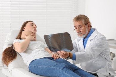 Photo of Orthopedist showing X-ray picture to patient in clinic