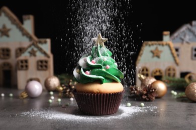 Sprinkling powdered sugar on Christmas tree shaped cupcake