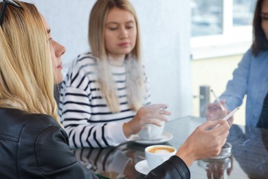 Photo of Women smoking cigarettes at table in outdoor cafe