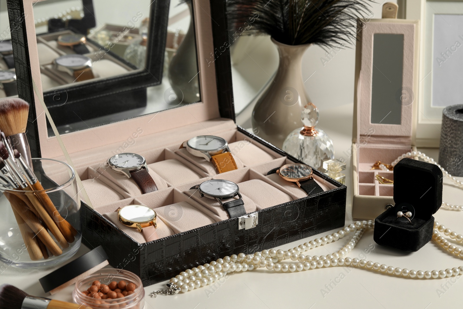 Photo of Jewelry boxes with many stylish wristwatches, accessories, perfumes, makeup brushes and decor on white table