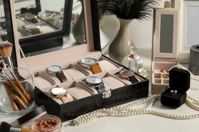 Jewelry boxes with many stylish wristwatches, accessories, perfumes, makeup brushes and decor on white table