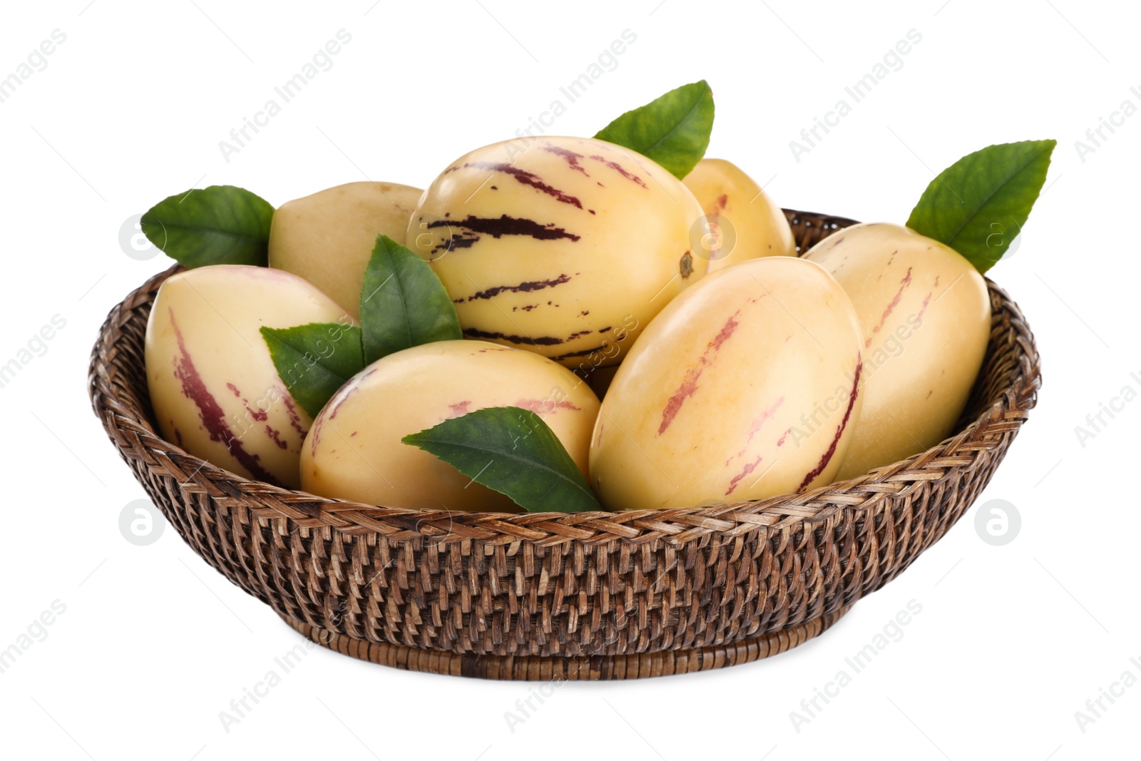 Photo of Fresh ripe pepino melons with green leaves in wicker bowl on white background