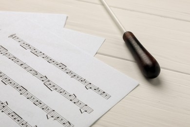Photo of Conductor's baton and sheet music on white wooden table