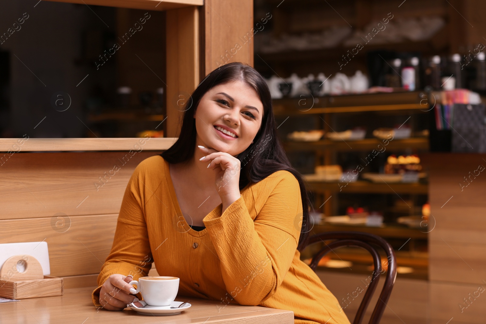 Photo of Beautiful overweight woman at table in cafe. Plus size model