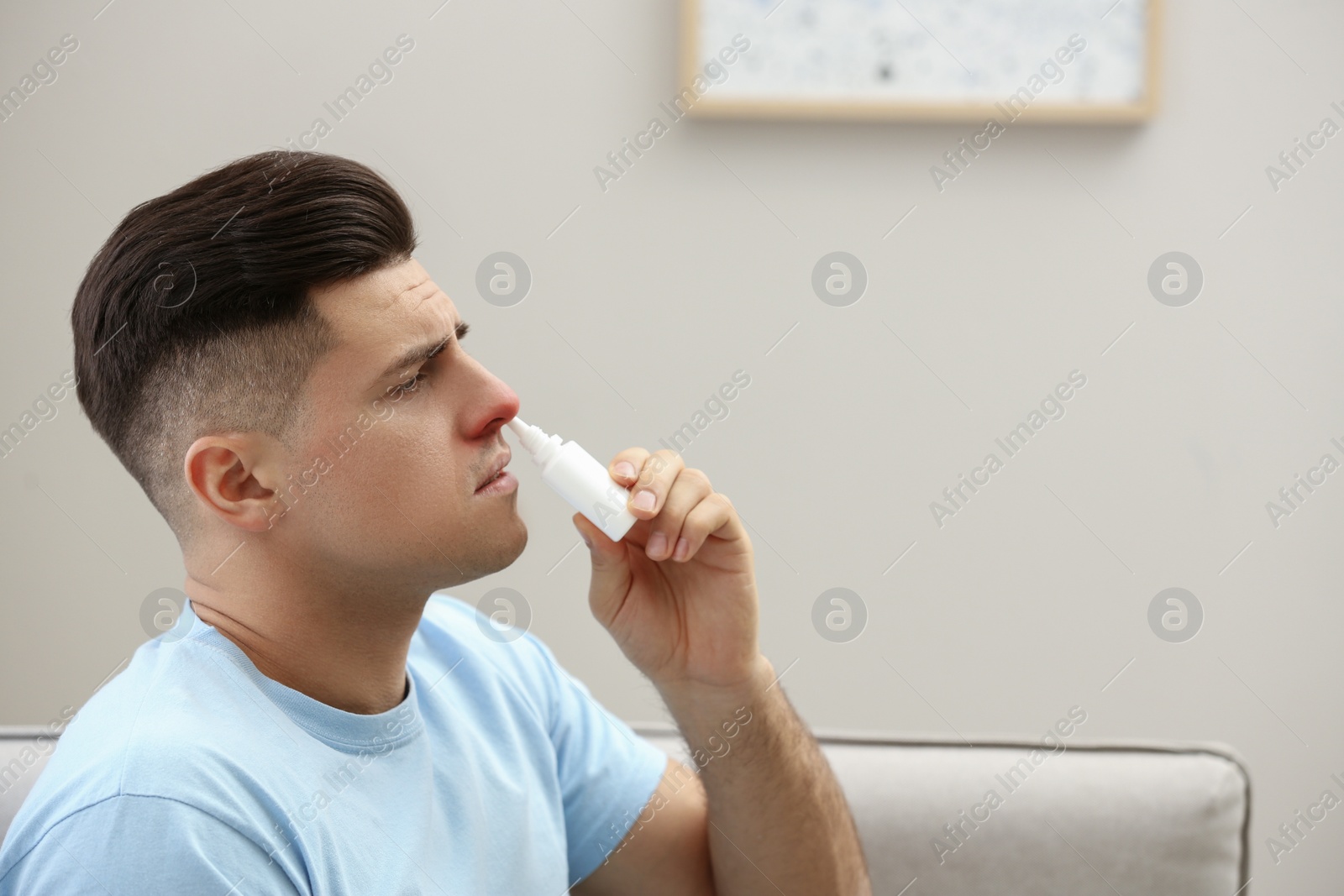 Photo of Ill man using nasal spray at home