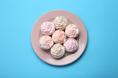 Photo of Plate with tasty cupcakes on light blue background, top view