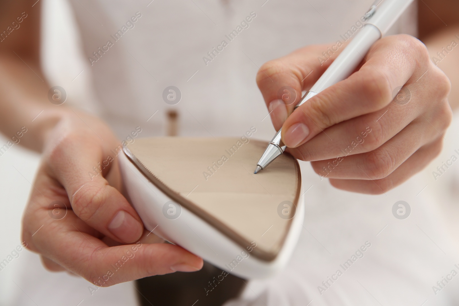 Photo of Young bride writing on her shoe indoors, closeup. Wedding superstition