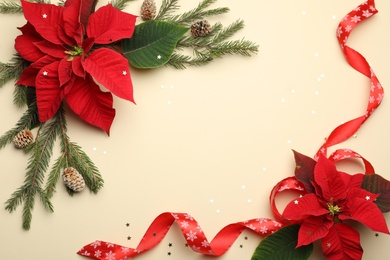 Photo of Flat lay composition with poinsettias (traditional Christmas flowers) and fir branches on beige background. Space for text