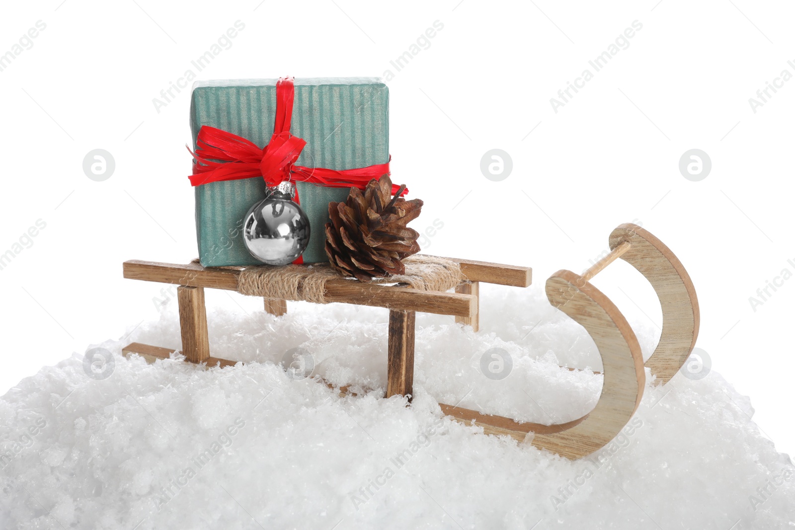 Photo of Wooden sleigh with gift box, Christmas ball, pine cone and artificial snow on white background