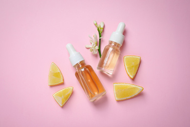 Photo of Flat lay composition with bottles of citrus essential oil on pink background