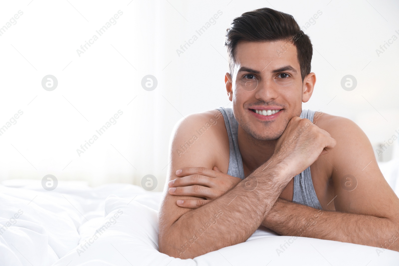 Photo of Portrait of happy handsome man lying on large bed