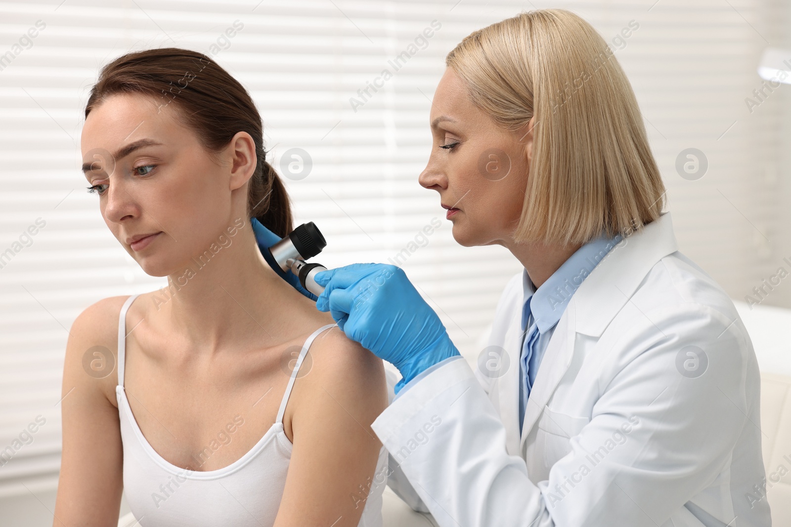 Photo of Dermatologist with dermatoscope examining patient in clinic