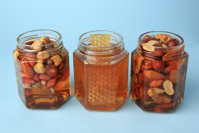 Photo of Jars with different nuts and honey on light blue background