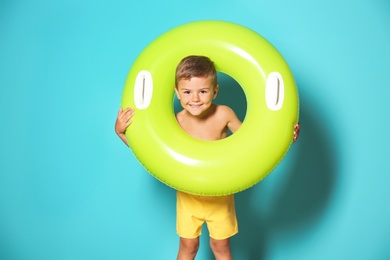 Cute little boy with inflatable ring on color background