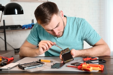 Photo of Technician repairing mobile phone at table in workshop