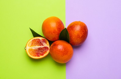 Photo of Ripe sicilian oranges and leaves on color background, flat lay