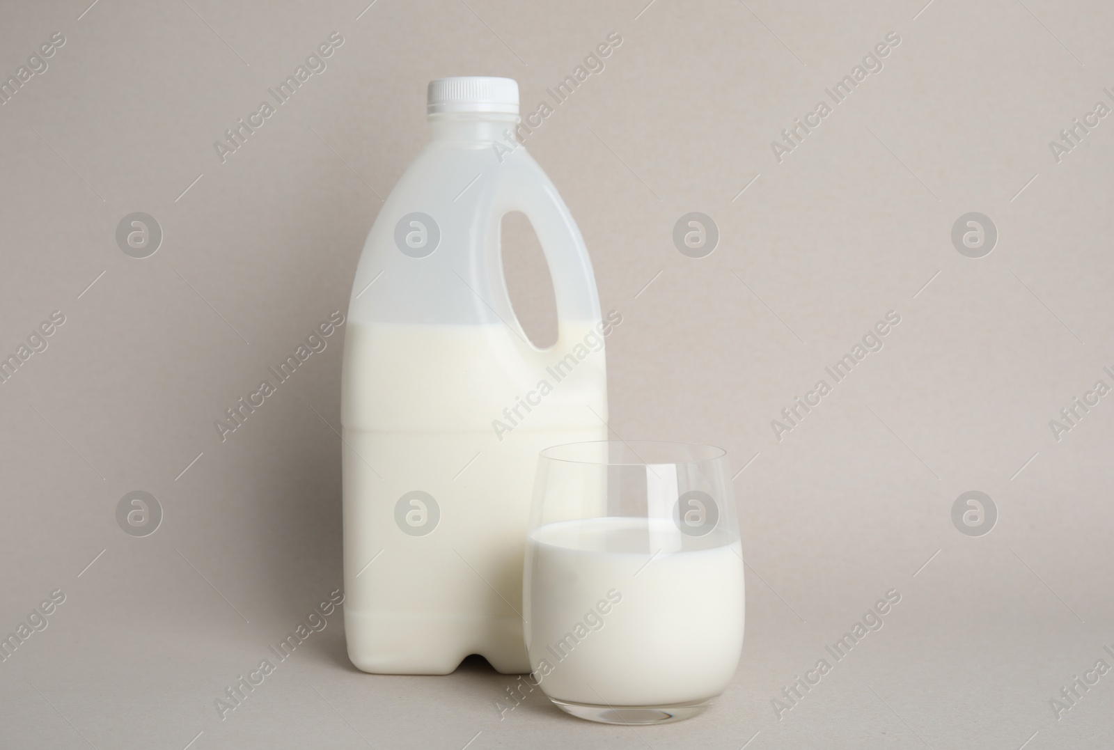 Photo of Gallon bottle and glass of milk on beige background