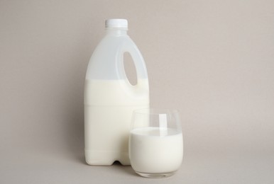 Gallon bottle and glass of milk on beige background