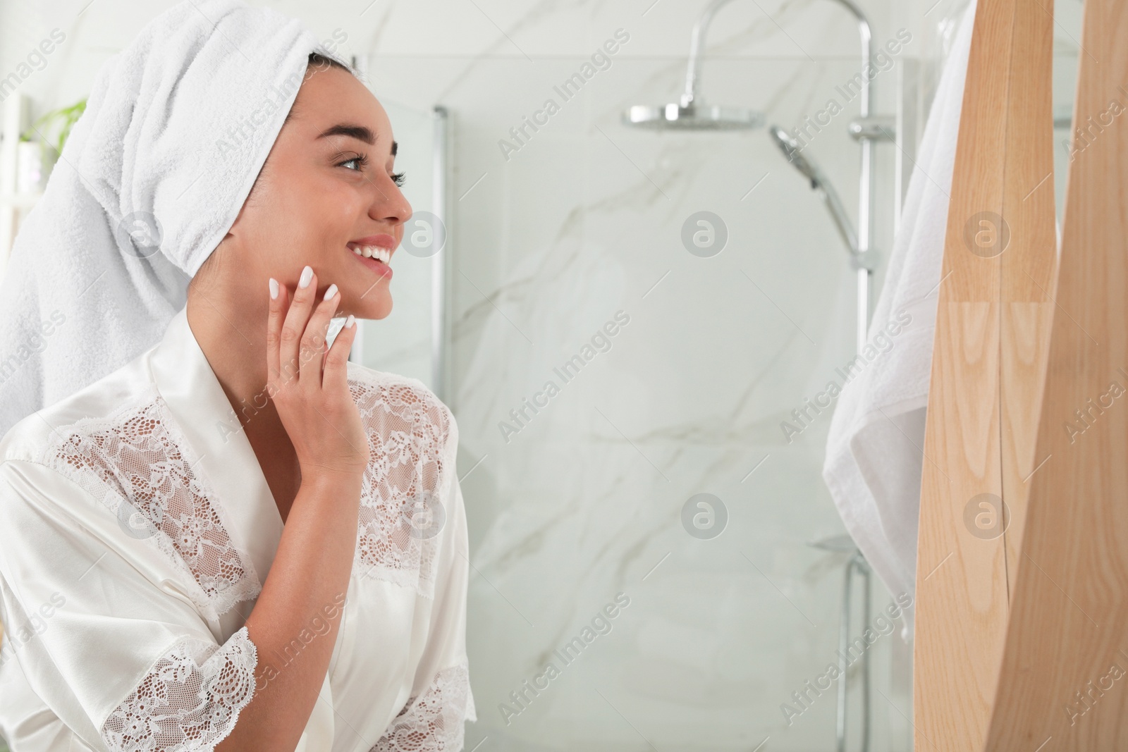 Photo of Beautiful young woman with perfect skin near mirror in bathroom, space for text. Facial wash