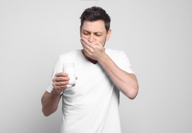 Man with glass of milk suffering from lactose intolerance on white background